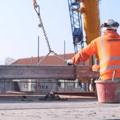 Milbank site employee crouches with hollowcore flooring plank