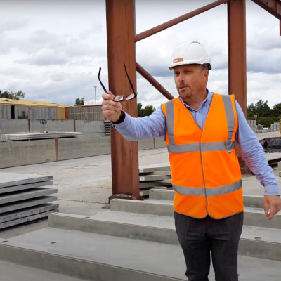 Mark Ellis holds glasses whilst standing on precast concrete stadium units